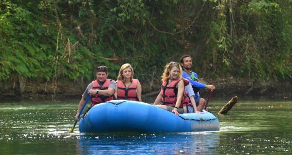 Arenal Water Activities Image: Four travelers sit in a blue raft, gliding down a river.