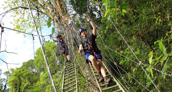 Arenal Rappelling Tours Image: Two people walk across hanging ladders on the Sky Limit tour.