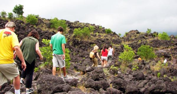Arenal Volcano Tour Image: Six people walk across jagged terrain on an Arenal Volcano hike.
